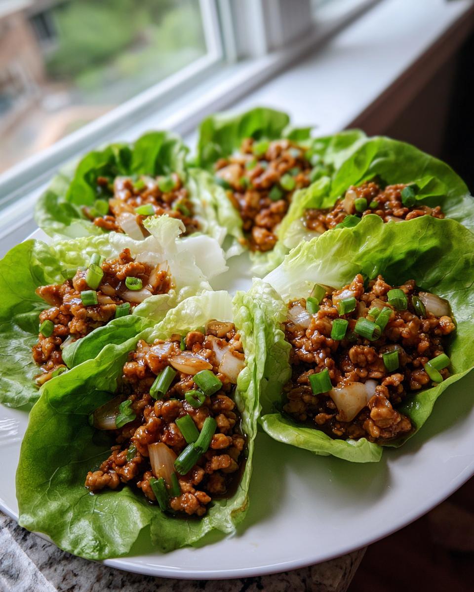 Four servings of flavorful chicken lettuce wraps filled with ground chicken mixture and topped with green onions.