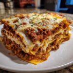 A thick, cheesy slice of homemade lasagna with rich meat sauce layers, garnished with parsley.