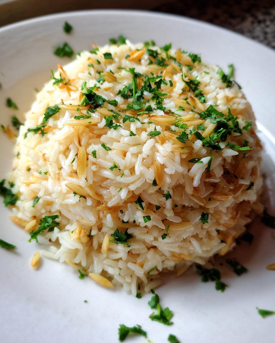A mound of fluffy rice pilaf mixed with toasted vermicelli and topped with fresh parsley.