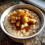 A close-up of creamy apple cinnamon oatmeal topped with caramelized apple chunks and cinnamon syrup.