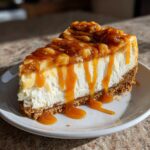 A decadent slice of apple pie cheesecake topped with chunky apple filling and dripping caramel sauce.