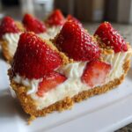 Close-up of a slice of no-bake cheesecake deviled strawberries with a graham cracker crust and whipped topping.