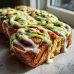 Close-up of freshly baked christmas tree cinnamon rolls drizzled with white and green icing.