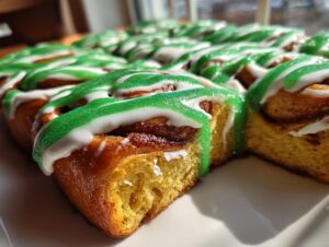 Close-up of freshly baked christmas tree cinnamon rolls topped with white and sparkling green icing.