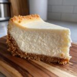 A thick, creamy slice of perfect cheesecake with a graham cracker crust, showcasing the texture of the cheesecake recipe.