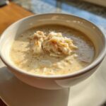 A close-up of a bowl of creamy she crab soup garnished generously with white lump crab meat.