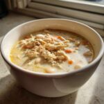 A close-up of a creamy white chicken chili bowl topped with shredded white chicken and white beans.