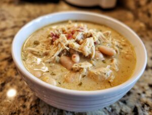 Close-up of a bowl of creamy white chicken chili featuring shredded white chicken and beans.