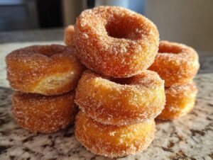 A close-up stack of fluffy mini donuts coated generously in cinnamon sugar.