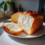 Close-up of a freshly baked japanese milk bread loaf, showing its incredibly soft, white, and fluffy interior texture.