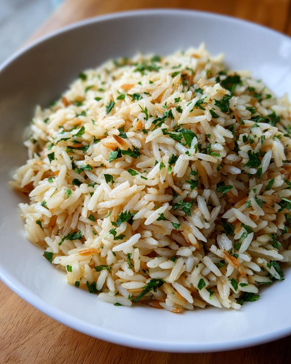 Close-up of a white bowl filled with fluffy rice pilaf recipe, garnished with chopped green parsley.