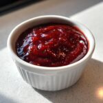 Close-up of thick, dark red homemade bbq sauce served in a small white ramekin.