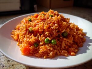 A mound of vibrant orange Mexican rice mixed with bright green peas and diced carrots served on a white plate.