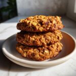 Three hearty, golden-brown oatmeal breakfast cookie stacked on a small, light-colored plate.