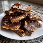 A pile of broken pieces of peanut butter pretzel bark featuring layers of chocolate, peanut butter filling, and sea salt.