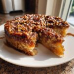 A slice cut from a rich pecan upside down cake, featuring a gooey caramel pecan topping.
