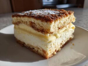 A close-up of a single, tall slice of bee sting cake showing layers of sponge, cream, and caramelized topping.
