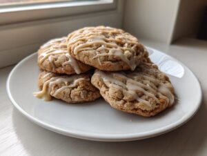 A stack of four delicious maple cookies drizzled with a light brown glaze, resting on a white plate.