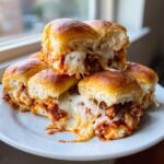 A stack of gooey, cheesy pizza sliders with melted mozzarella cheese stretching between the halves.