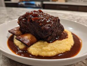 A single serving of tender braised short ribs glazed with dark sauce, served over creamy polenta.