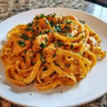 A close-up of creamy Cajun chicken pasta featuring fettuccine noodles, seasoned chicken pieces, and fresh parsley.