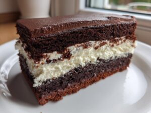 A rich slice of chocolate italian love cake featuring dark chocolate sponge layers and a thick white cream filling, served on a white plate.