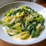 Close-up of tender braised leeks coated in a creamy sauce and seasoned with pepper.