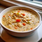 Close-up of a hearty bowl of creamy chicken wild rice soup with chunks of carrots and celery.