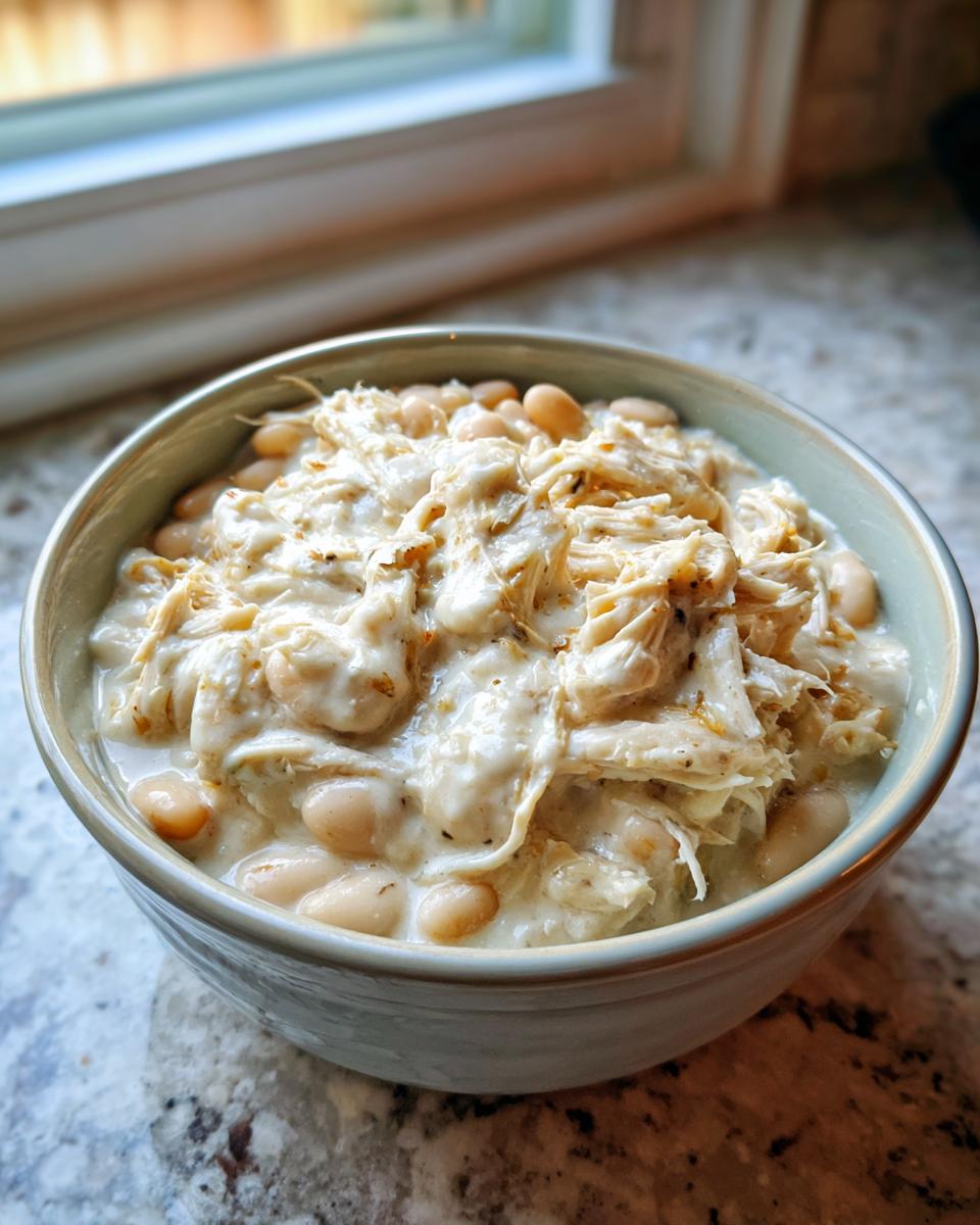 Close-up of a bowl filled with creamy white chicken chili, featuring shredded chicken and white beans.