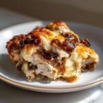A close-up of a serving of french onion chicken topped with melted, browned cheese and caramelized onions.