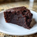 A close-up shot of a rich, fudgy slice of date brownies served on a white plate.
