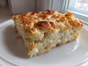 A close-up serving of creamy funeral potatoes recipe with a golden, crispy cheese topping on a white plate.