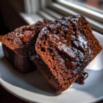 Two thick slices of moist hot fudge brownie bread topped with melted chocolate sauce.
