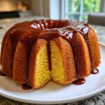 A golden yellow Bacardi Rum Cake in a bundt shape, generously covered with a dark rum glaze dripping down the sides.