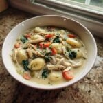 A close-up of creamy homemade Olive Garden Chicken Gnocchi Soup filled with tender gnocchi, shredded chicken, carrots, and spinach.