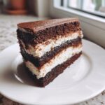 A decadent slice of multi-layered Italian love cake featuring dark chocolate cake and white cream filling.