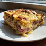 A hearty, square slice of homemade reuben bake featuring layers of corned beef, sauerkraut, and a crispy, cheesy topping.