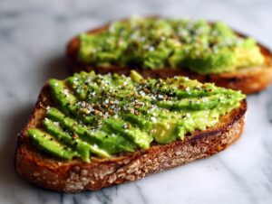 Close-up of two slices of perfect avocado toast topped with sliced avocado and everything bagel seasoning.