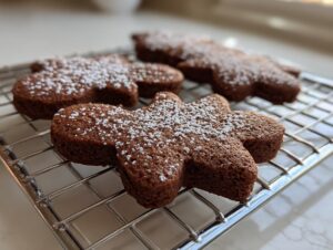 Close-up of soft gingerbread cookies dusted with powdered sugar cooling on a wire rack.