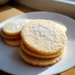 Close-up of a stack of soft sugar cookie rounds topped generously with coarse sparkling sugar.