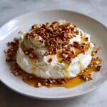 A mound of creamy whipped goat cheese topped with chopped nuts and drizzled with honey.