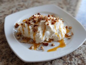 A serving of light and fluffy whipped goat cheese topped with chopped nuts and drizzled with honey or caramel.