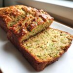 Close-up of freshly baked zucchini banana bread, sliced to show moist texture and green zucchini shreds.