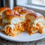 Close-up of cheesy buffalo chicken sliders cut in half, showing shredded orange buffalo chicken and melted white cheese.