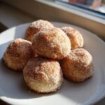 A pile of freshly baked cinnamon sugar snowball cookies coated heavily in sparkling sugar and cinnamon mix.