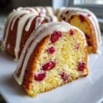 Close-up of a slice of moist cranberry orange cake topped with thick white citrus glaze.