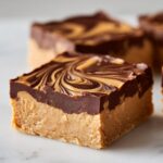 A close-up of a rich, creamy peanut butter bars square with a thick chocolate topping featuring a peanut butter swirl.