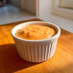 Close-up of creamy, orange-hued smash burger sauce served in a small white fluted ramekin.