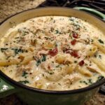 Close-up of creamy white chicken lasagna soup with penne pasta, shredded chicken, and cheese topping.