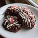 Three rich, dark double chocolate peppermint cookies drizzled with white icing and topped with crushed candy canes.
